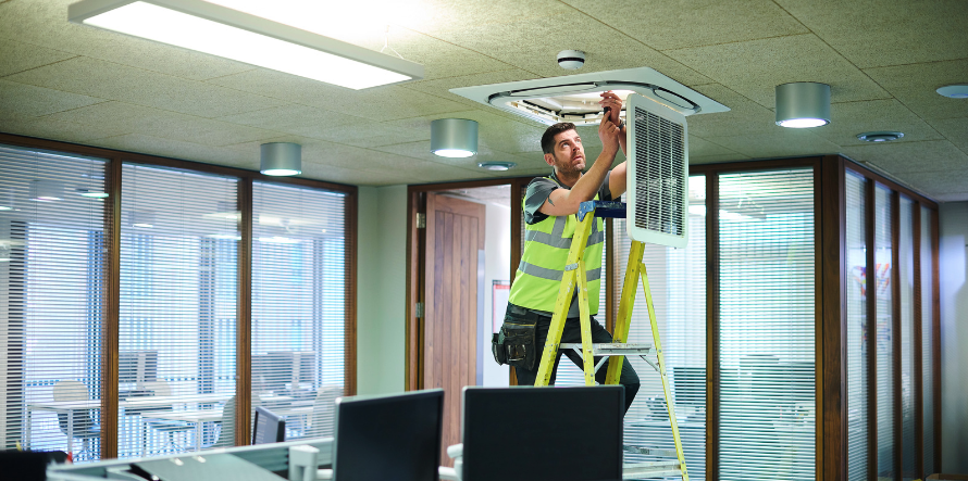 facilities management worker fixing ceiling vent