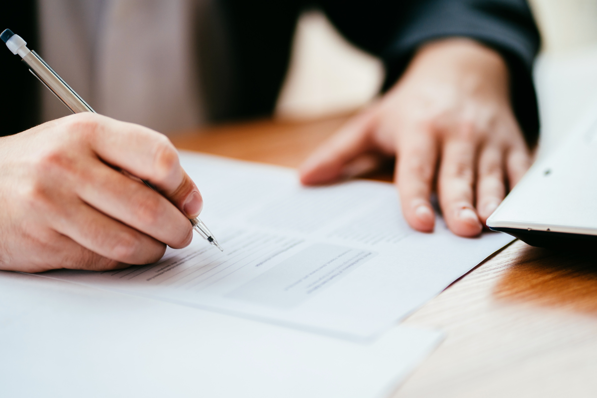 man signing contract on desk